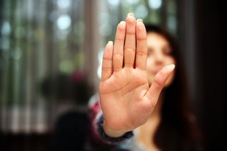 Woman with her hand extended signaling to stop (only her hand is in focus).jpeg